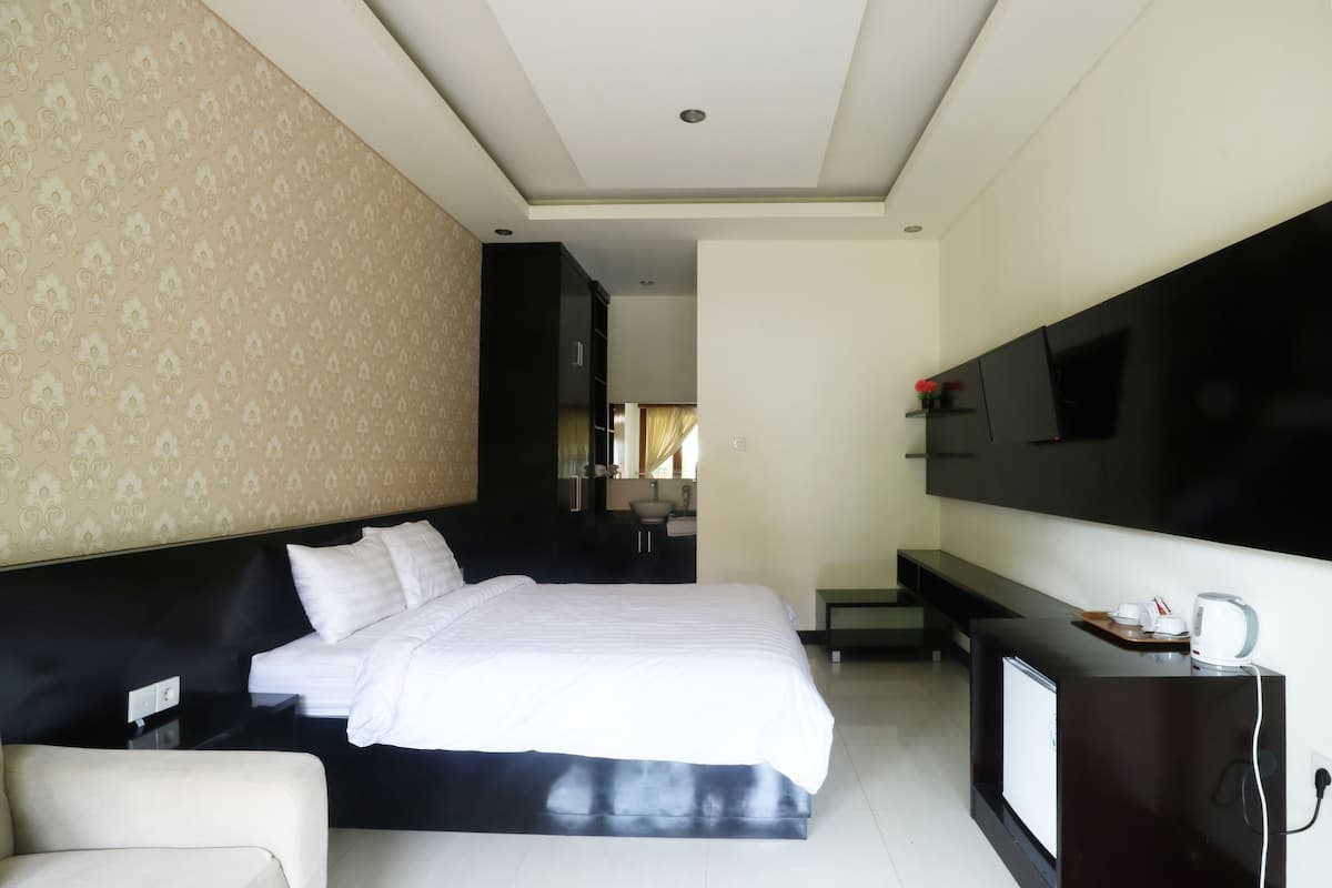 Une chambre d’hôtel avec un grand lit, un téléviseur fixé au mur, un bureau avec une bouilloire et une vue sur la salle de bain.