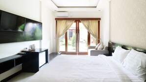 Ein modernes Hotelzimmer mit einem großen Bett, einem wandmontierten Flachbildfernseher, einem Schreibtisch mit Stuhl und einer Glastür zum Balkon.