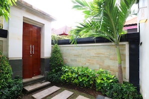 A residential entrance with a wooden door, stone steps, and a stone wall. - The Umah Pandawa Homestay and Villas (Kutuh)