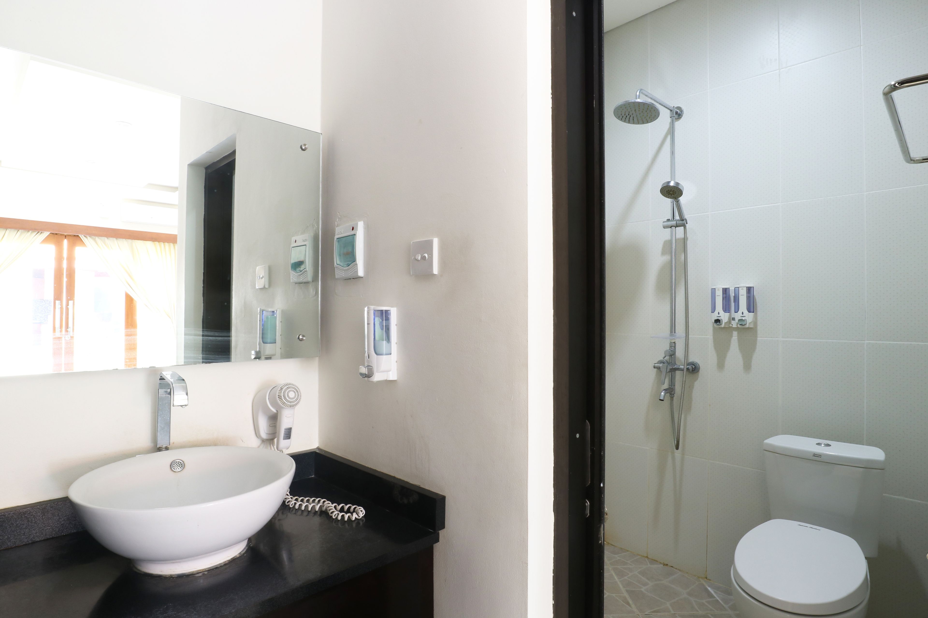 Un baño con lavamanos blanco, espejo, ducha e inodoro.