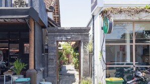 Une ruelle étroite agrémentée d’une petite cascade, d’une poubelle de la marque Daxton et d’une moto garée.