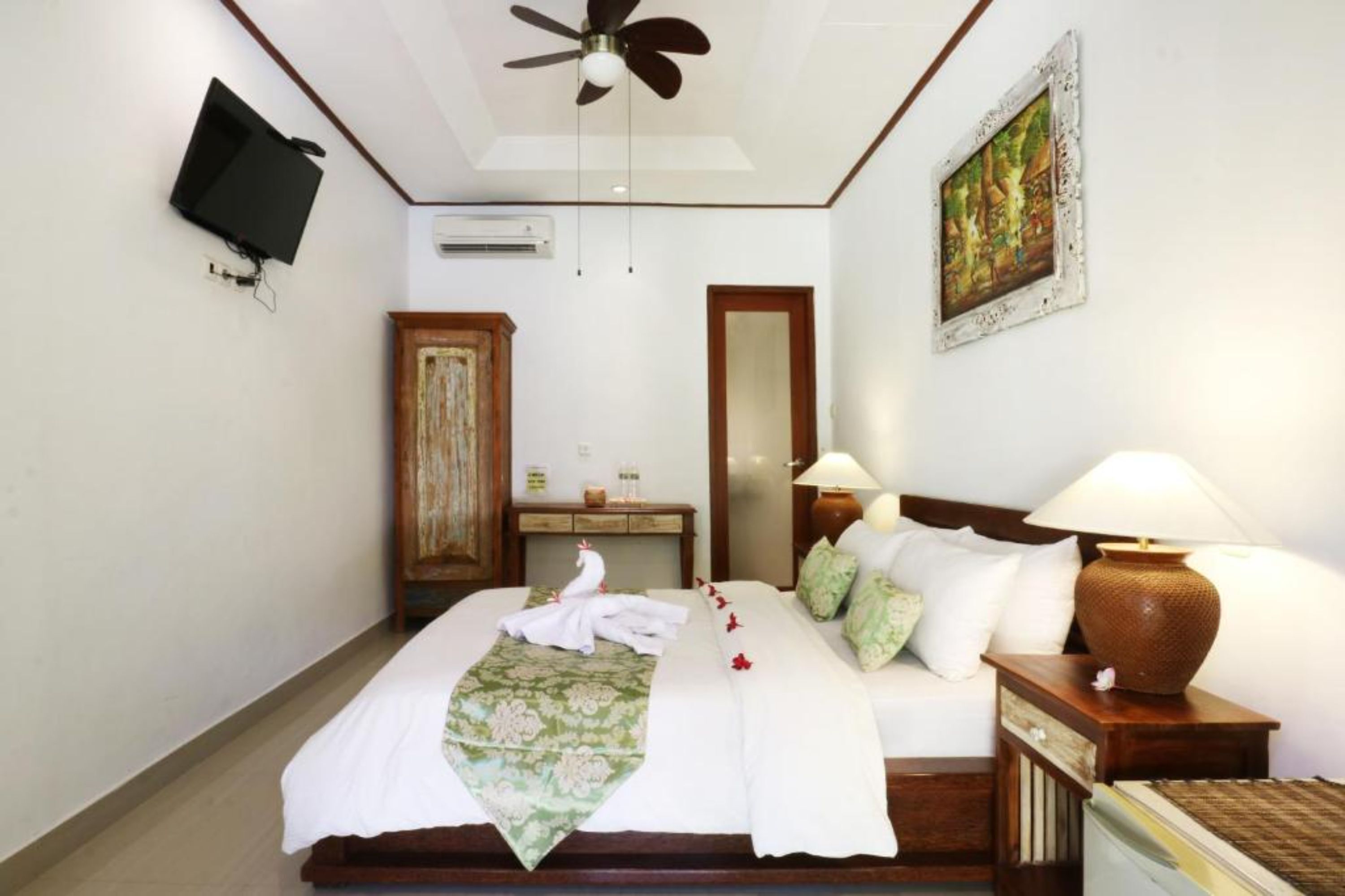 A hotel room with a bed, bedside table, lamp, and a painting on the wall.