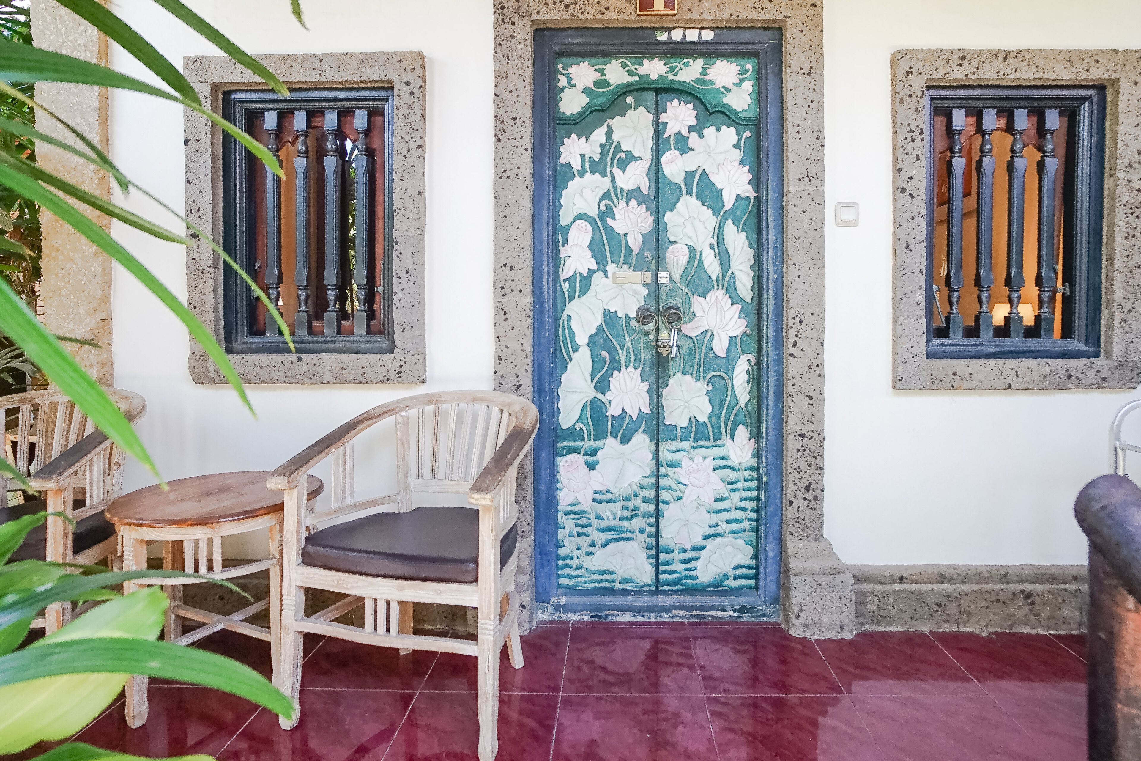 A traditional wooden door with floral designs, flanked by two windows with metal bars.