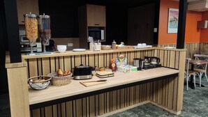 Una barra de desayuno con cafetera, tostadora y diversos alimentos.