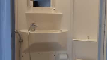 Un baño pequeño y funcional con inodoro, lavamanos y zona de ducha.