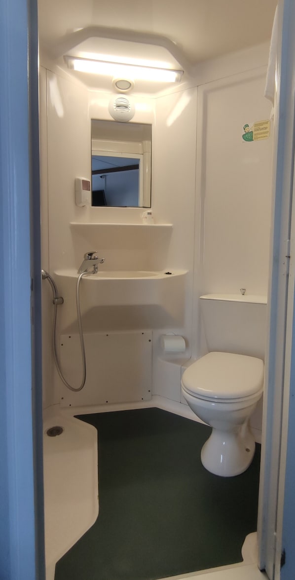 A small, compact bathroom with a toilet, sink, and shower area. - Fasthotel Laval (Laval)