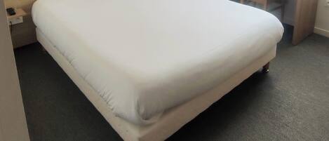 Una habitación de hotel con cama, escritorio, armario y ventana con cortinas.