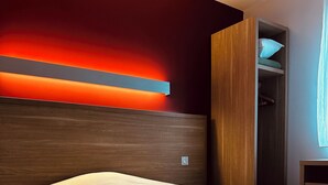 Una habitación de hotel con una cama grande, un cabecero de madera y un armario empotrado.