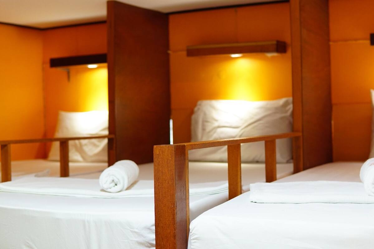 Ein Hotelzimmer mit zwei Betten, jeweils mit einem Holz-Kopfteil und weißer Bettwäsche.