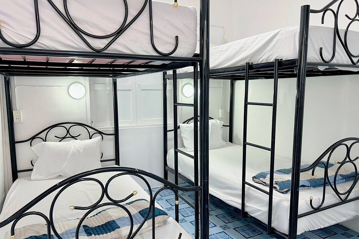 Ein Zimmer mit Etagenbetten, weißer Bettwäsche und einem gemusterten Boden.