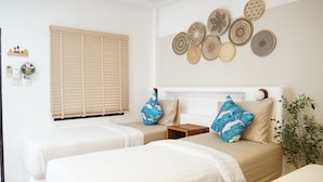 A bedroom with two beds, a window with blinds, and decorative wall hangings. - Yoghurt Home (Ko Pha-ngan)