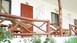 A wooden structure with ropes forming hammocks, a wooden door, and a white wall with a decorative panel. - Yoghurt Home (Ko Pha-ngan)