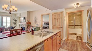 A modern kitchen with a large island, a built-in oven, and a dining area with wooden chairs.