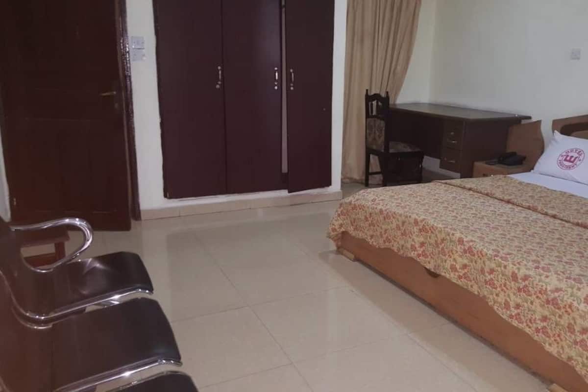 A bedroom with a bed, a desk, a chair, and a wardrobe.