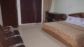 A bedroom with a bed, a desk, a chair, and a wardrobe. - Hotel President (Accra)