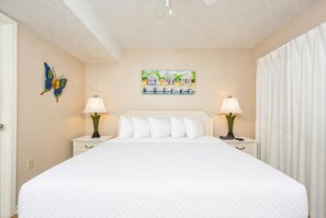 A hotel room with a large bed, two bedside tables with lamps, a wall painting, and a butterfly decoration.