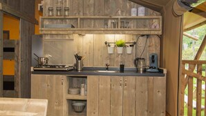Una cocina rústica con armarios de madera, una estufa y macetas colgantes.