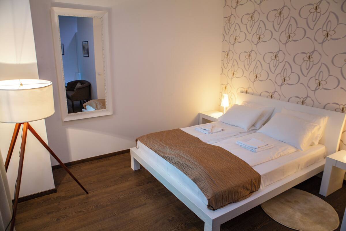 A neatly made bed with a brown blanket, a bedside lamp, and a nightstand.