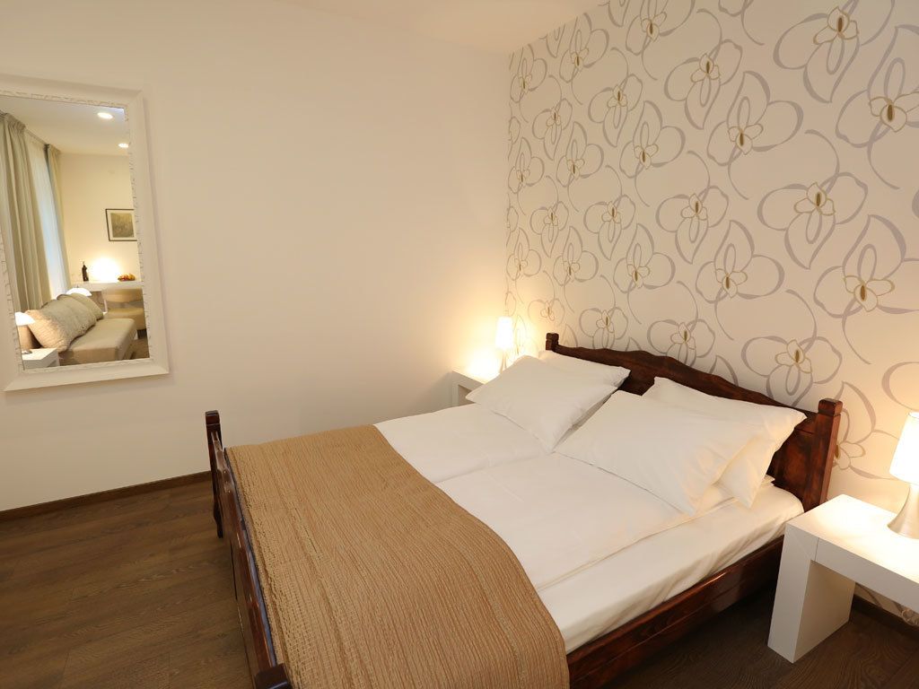 A bedroom with a bed, bedside tables, and a mirror.