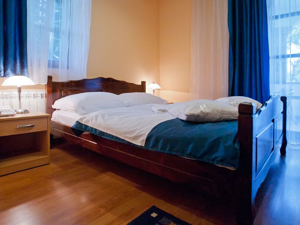 A single bed with a wooden frame, two bedside tables, and a nightstand.