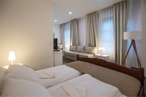 Una habitación de hotel con dos camas, un sofá, un televisor y una lámpara.