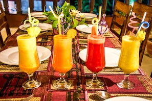 A table with four drinks in glasses, each with a straw and a garnish.