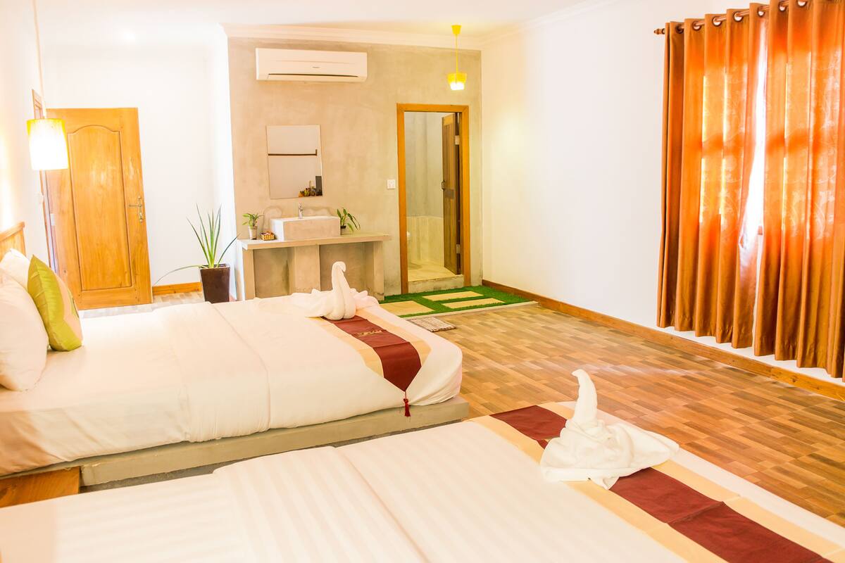 Ein Hotelzimmer mit einem großen Bett, einem kleinen Badezimmer und einem Holzboden.