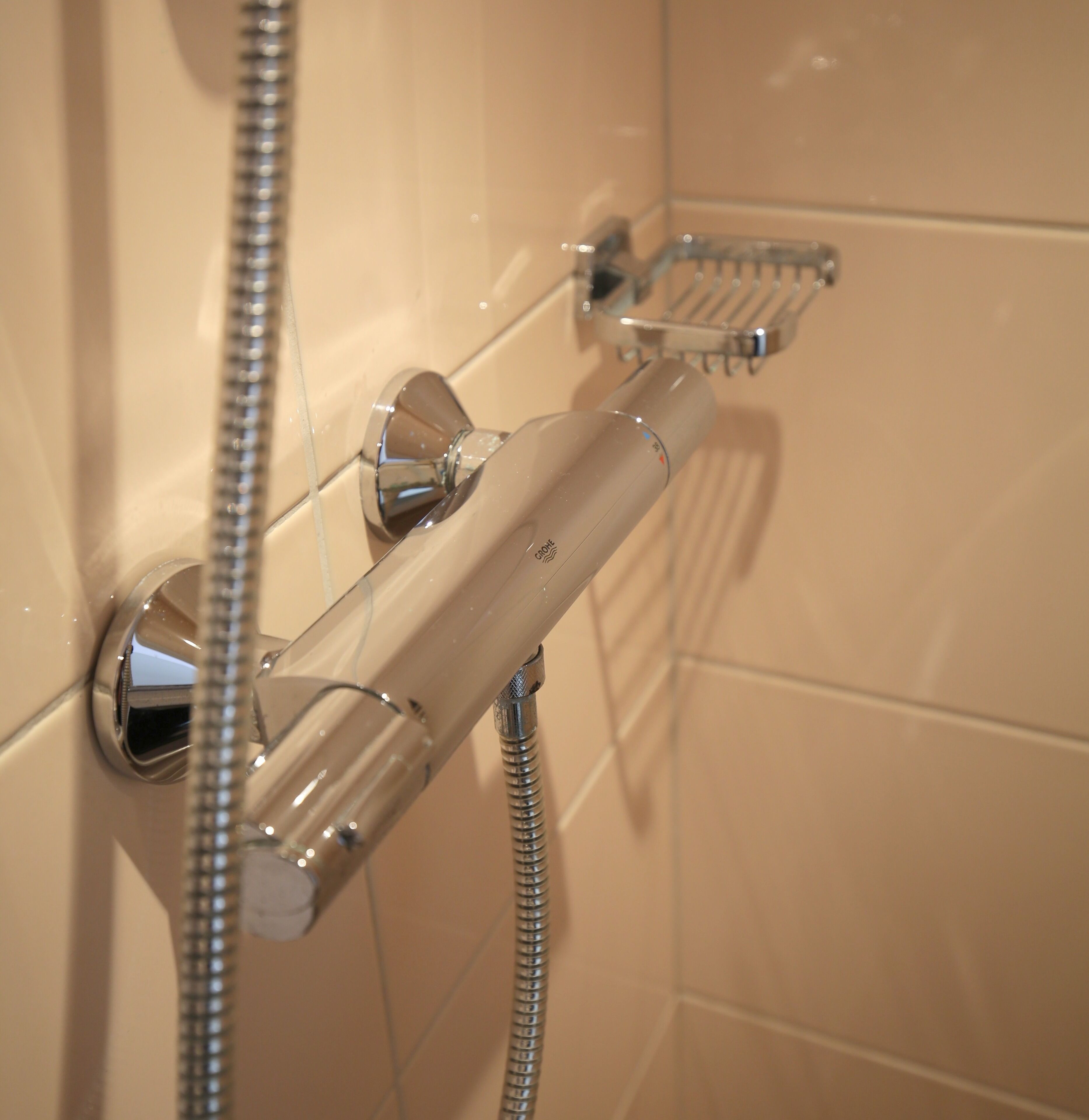 A shower with chrome fixtures and a handheld showerhead.