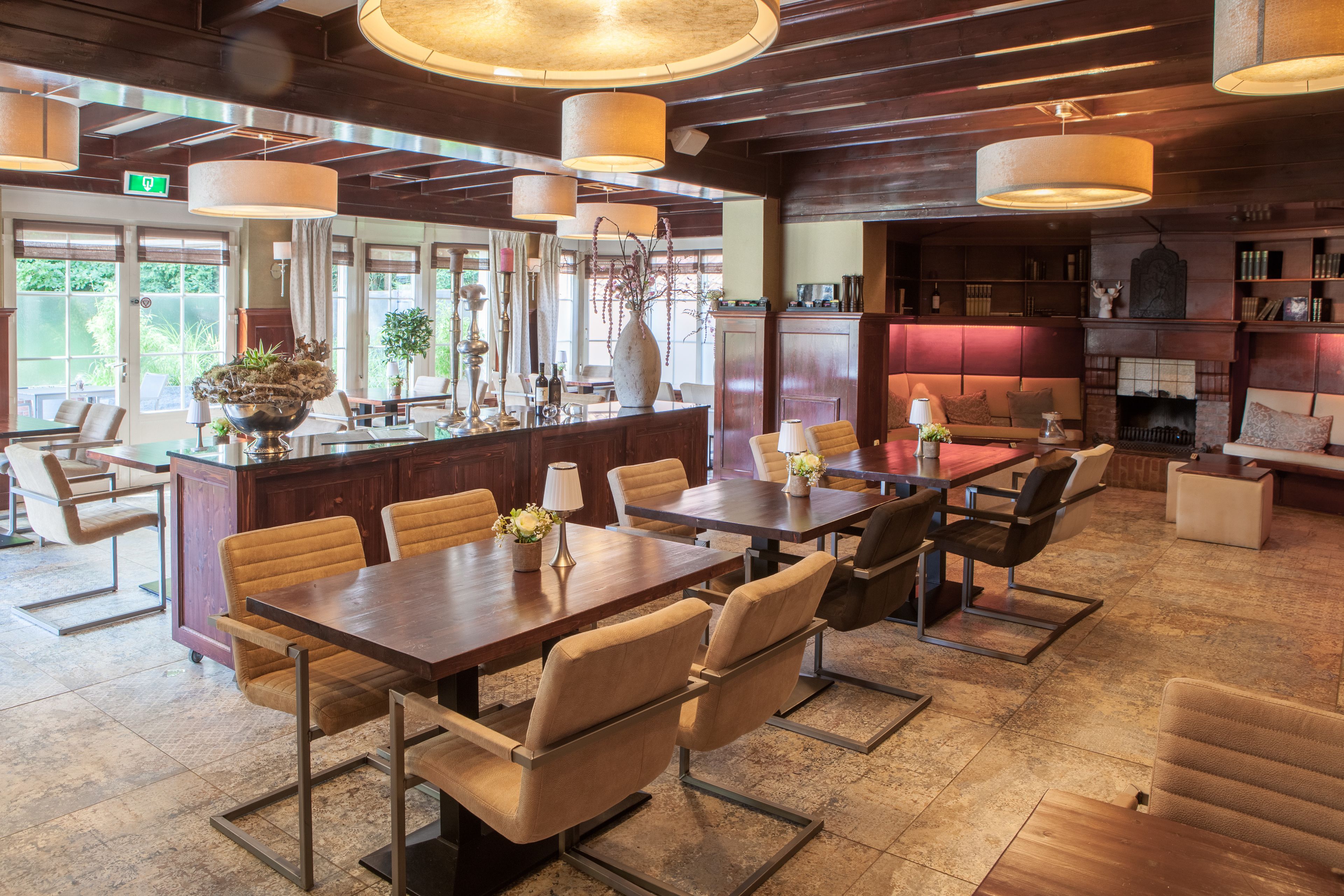 A spacious dining area with a long wooden table and multiple chairs, a bar area with a counter and stools, and a fireplace.