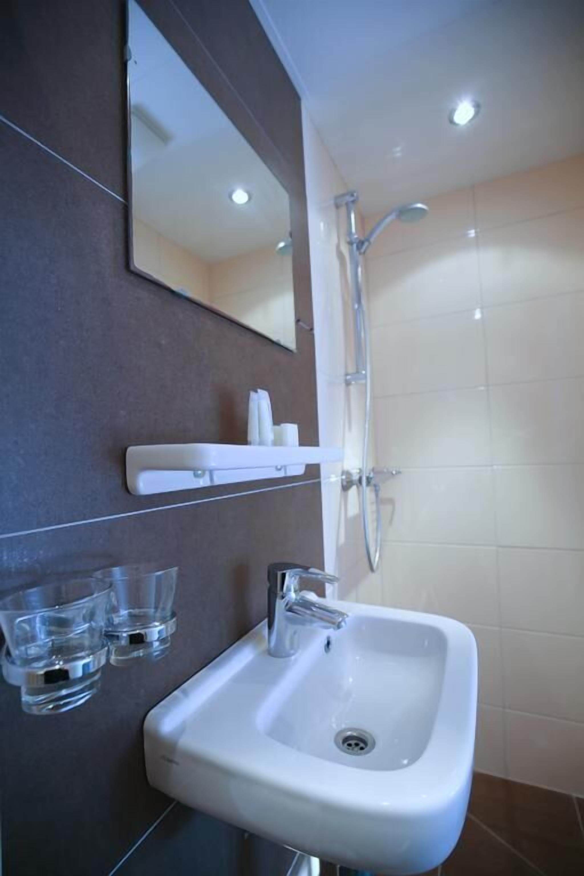 A bathroom with a white sink, a mirror, and a shower.