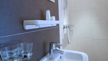 A bathroom with a white sink, a mirror, and a shower.