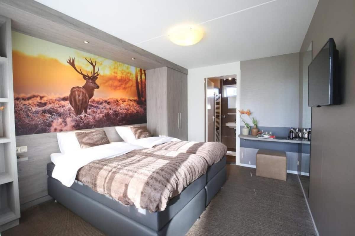 Un dormitorio moderno con una cama grande, un televisor de pared y un cuadro de un ciervo.
