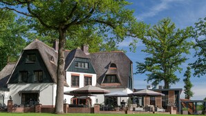 A large, traditional house with a steeply pitched roof, multiple windows, and a well-maintained lawn. - Huize Hölterhof (Enschede)