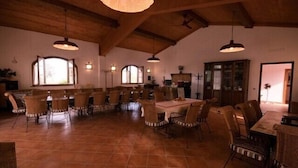 A spacious dining area with high ceilings and exposed beams, featuring multiple tables and chairs. - Agriturismo Signorini (Lajatico)