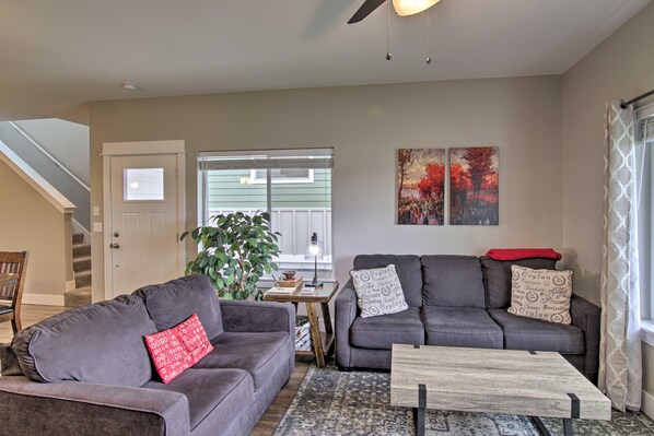 A living room with two grey sofas, a wooden coffee table, and a large window with blinds. - "Elegant Escape" (KING BED) Minutes From Downtown (Bozeman)