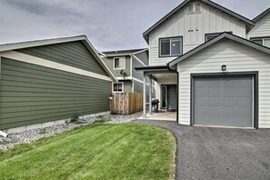 En bostadsbyggnad med garage, en täckt uteplats och en välskött gräsmatta.