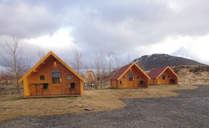 Cabins offer a rustic retreat amidst the mountains, each with a front door, windows, and a cozy porch.