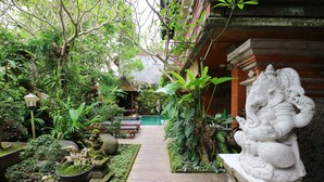 A garden pathway leading to a traditional building with a statue of an elephant deity. - Pering Bungalow Ubud (Ubud)