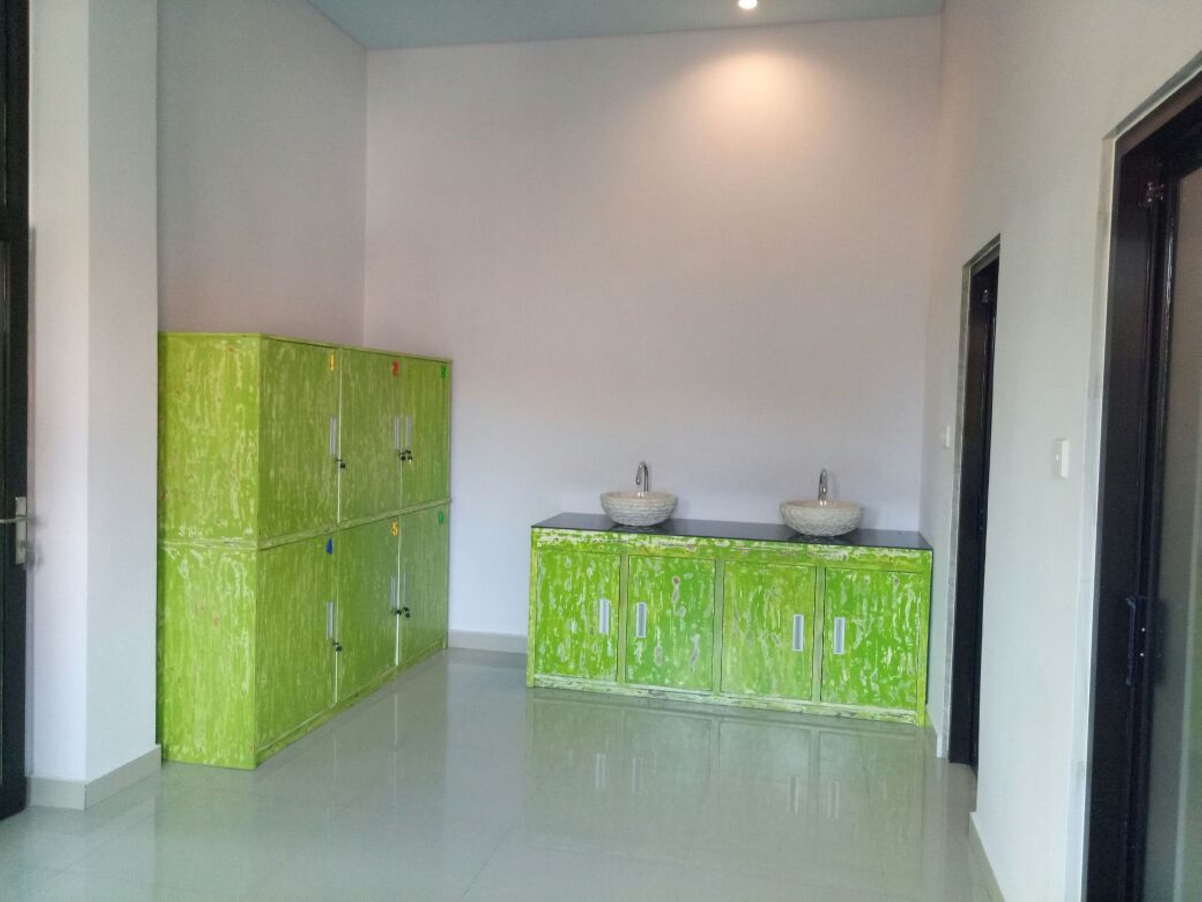 A hallway with green lockers and a sink area.