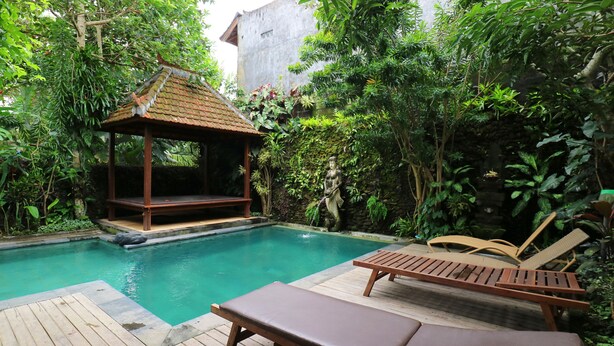 A pool area with a wooden deck, lounge chairs, and a gazebo. - Pering Bungalow Ubud (Ubud)