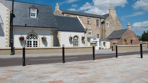 A traditional stone building with a pitched roof, arched windows, and flower boxes. - Dumfries Arms Hotel (Cumnock)