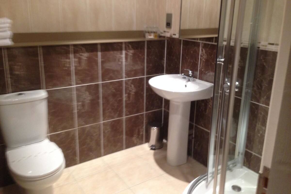 A bathroom with a toilet, sink, and glass shower enclosure.