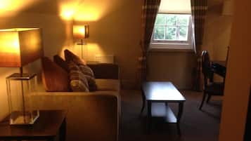 Une pièce confortable avec un canapé, une petite table et une fenêtre avec des rideaux.