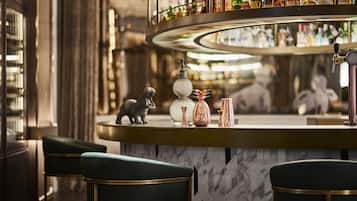 A bar area with a marble countertop, a variety of bottles, and a decorative dog figurine.