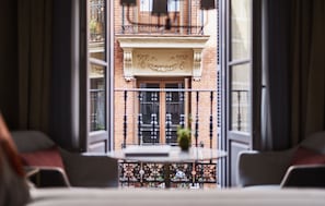 A view from a balcony with a table and chairs, a decorative iron railing, and a building facade with a balcony and windows. - Gran Hotel Inglés - The Leading Hotels of the World (Madrid)