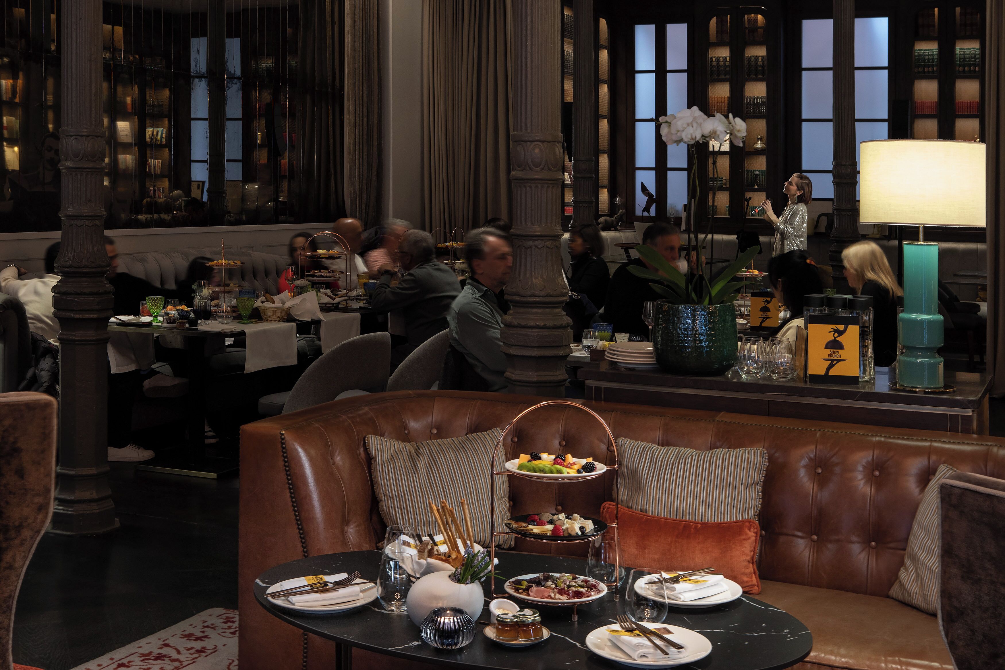 Un restaurant avec des sièges en cuir, un buffet et une grande fenêtre agrémentée d’étagères à livres.