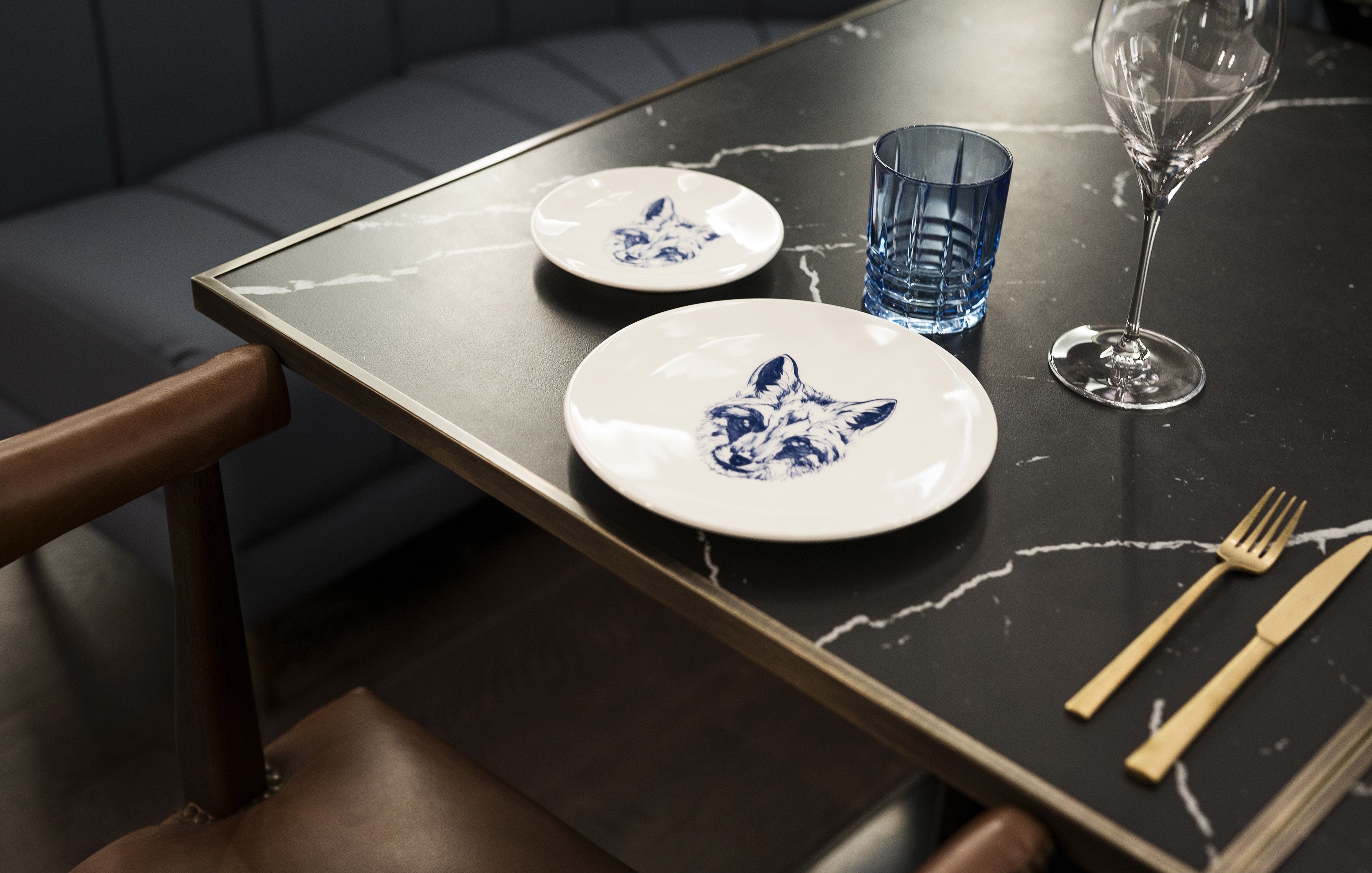 Una mesa de comedor con dos platos, una copa y cubiertos.