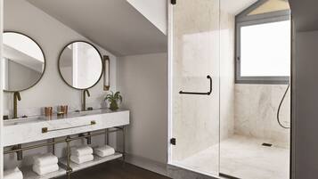 Une salle de bain moderne avec une douche à parois de verre, un meuble-lavabo en marbre avec des accessoires dorés et deux miroirs.