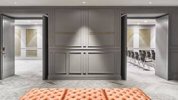 A hotel lobby with a grey tiled floor, a tufted orange sofa, and two doors labeled "SALON ANCH" and "SALON SANTA ANA".