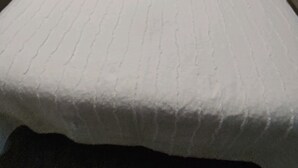 A neatly made bed with a white bedspread, two bedside tables with lamps, and a window with curtains.